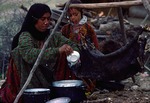 Woman filling goat skin bag with yoghurt to churn in Boir Ahmad by Reinhold Loeffler