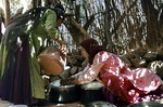 Girl assisting her mother with straining milk, Boir Ahmad