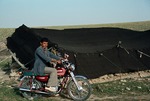 Man posing with motorbike before black tent of transhumance pastroralists, Boir Ahmad